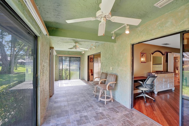 sunroom / solarium featuring rail lighting and ceiling fan