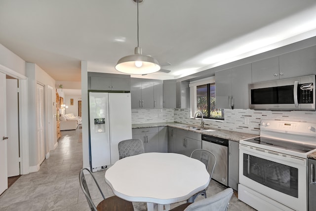 kitchen featuring hanging light fixtures, tasteful backsplash, gray cabinets, appliances with stainless steel finishes, and sink