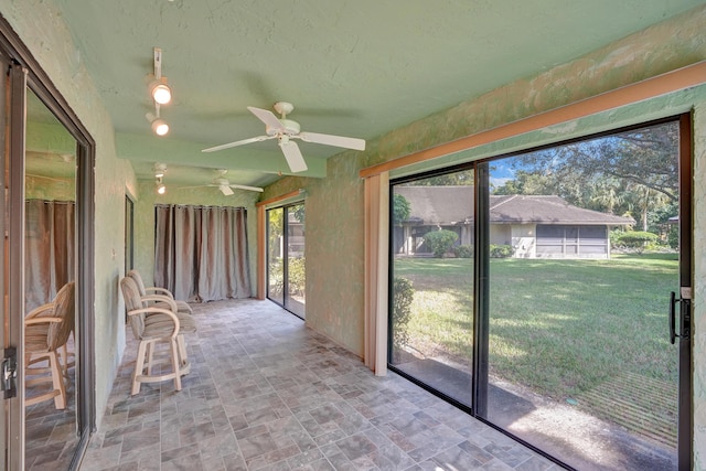 unfurnished sunroom featuring ceiling fan