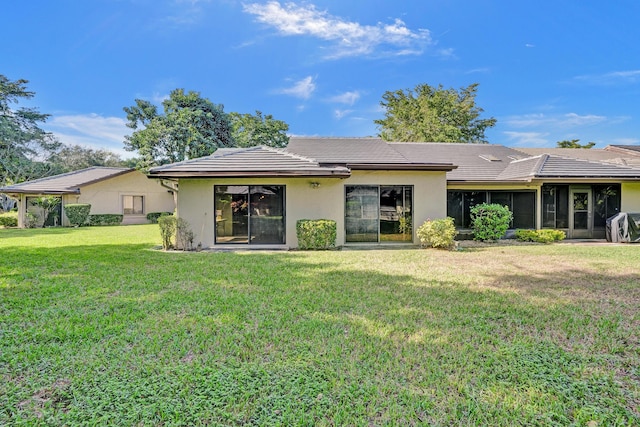 rear view of property with a yard and a sunroom