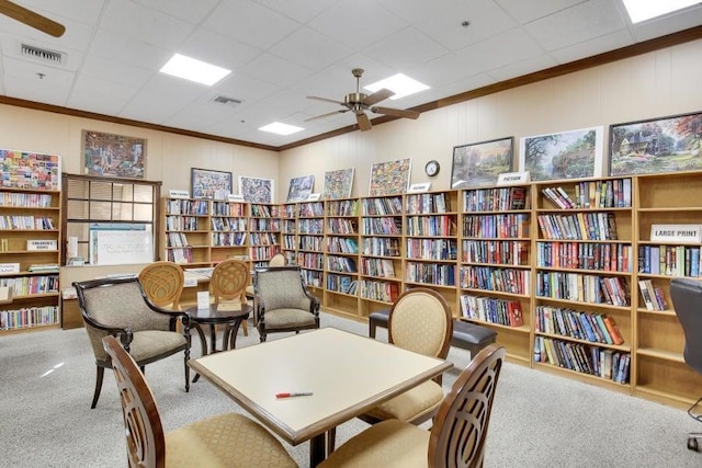 sitting room with a drop ceiling, ceiling fan, crown molding, and light colored carpet