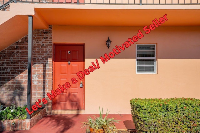 doorway to property featuring stucco siding and brick siding