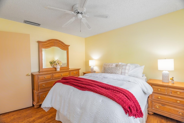 bedroom featuring ceiling fan, a textured ceiling, and hardwood / wood-style flooring