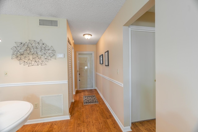 hall with wood-type flooring and a textured ceiling