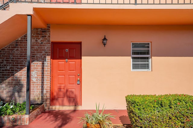 entrance to property featuring brick siding and stucco siding