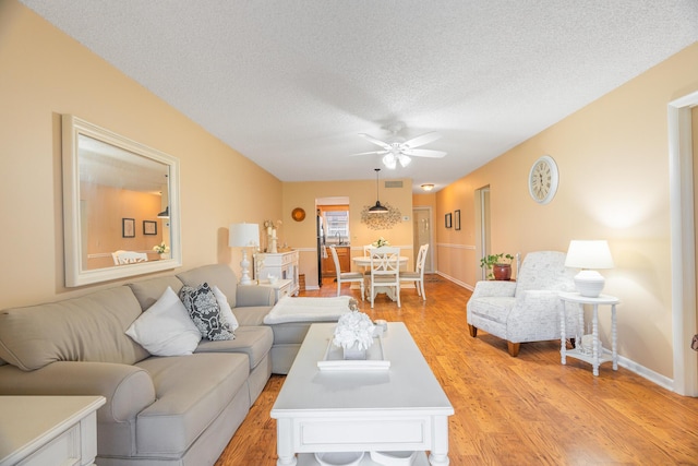 living room with ceiling fan, a textured ceiling, and light hardwood / wood-style flooring