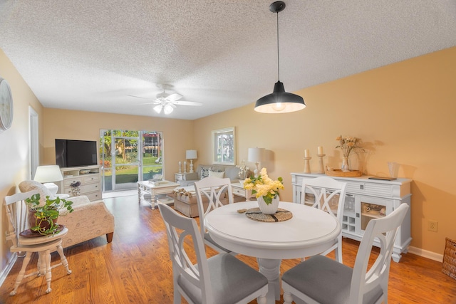 dining space featuring ceiling fan, light wood-type flooring, and a textured ceiling