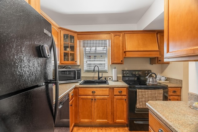 kitchen featuring custom range hood, sink, light hardwood / wood-style flooring, and black appliances