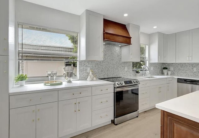 kitchen with premium range hood, backsplash, white cabinets, and appliances with stainless steel finishes