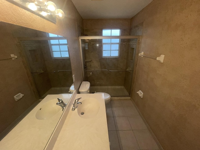 bathroom featuring tile patterned flooring, toilet, a shower with door, and sink