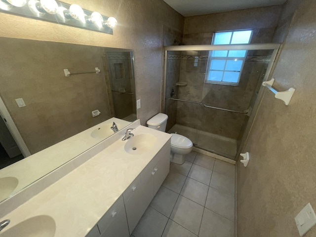 bathroom with tile patterned floors, a shower with door, vanity, and toilet