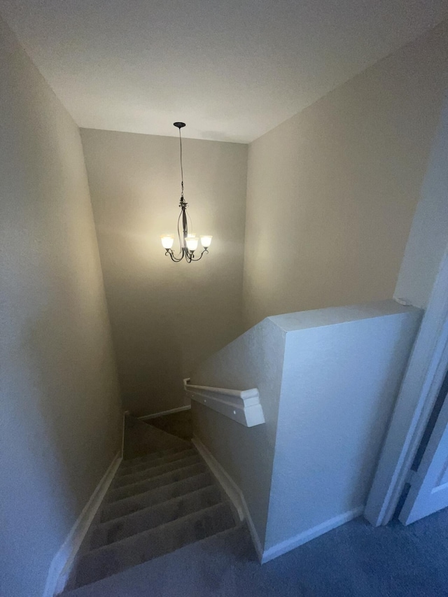 stairway with carpet flooring and a chandelier