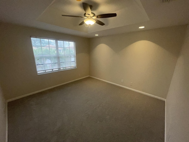 empty room featuring ceiling fan, carpet floors, and a tray ceiling