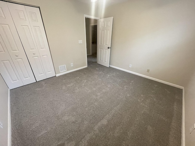 unfurnished bedroom featuring dark carpet and a closet