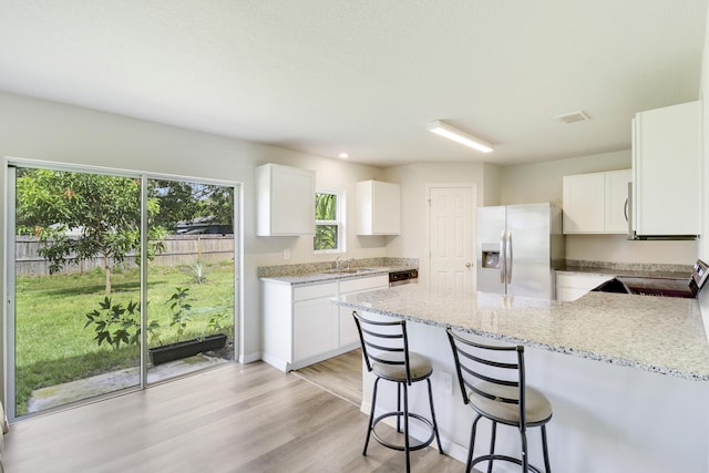 kitchen featuring white cabinets, appliances with stainless steel finishes, light stone countertops, and sink