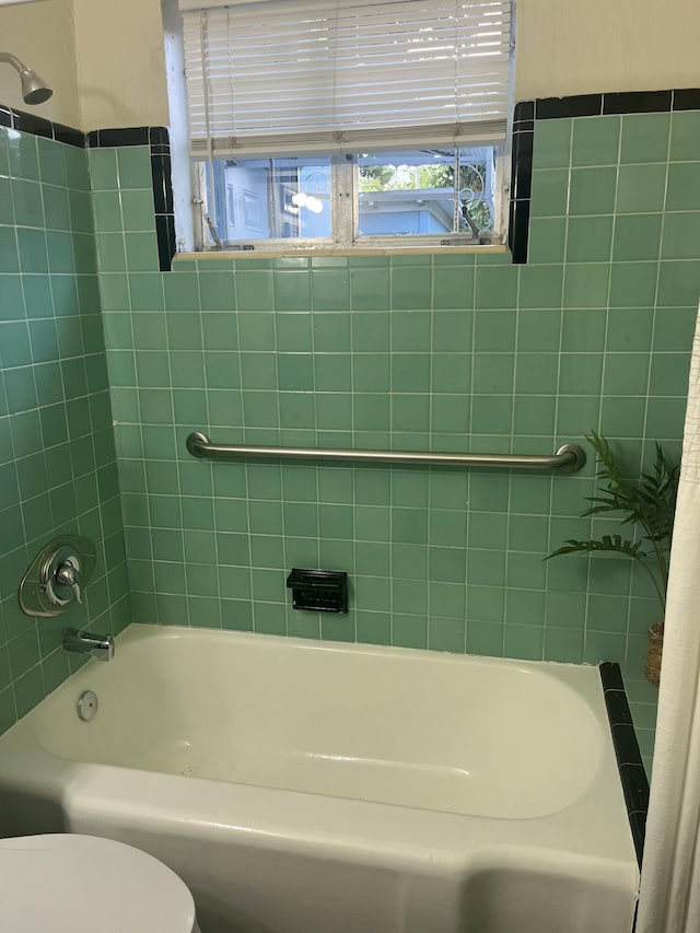 bathroom featuring tiled shower / bath combo and toilet