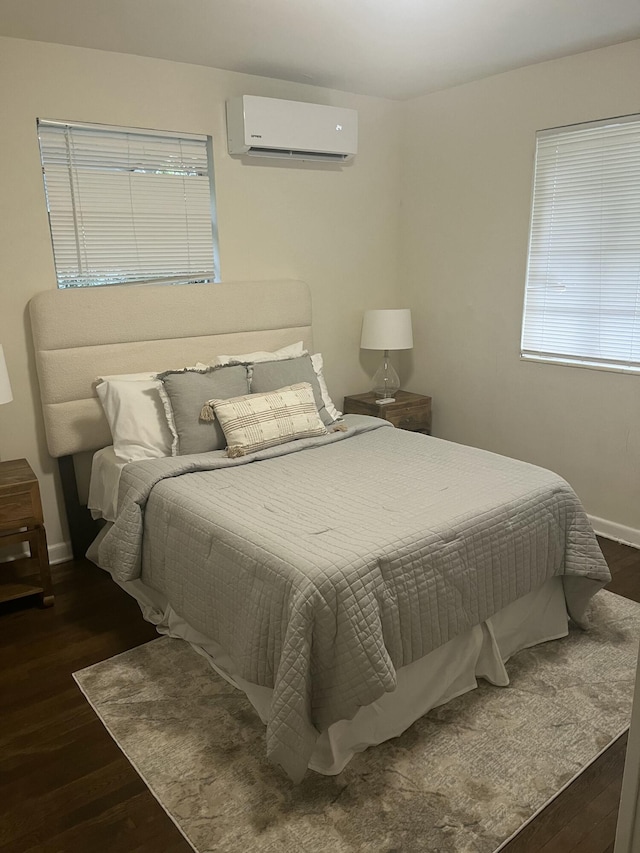 bedroom featuring dark hardwood / wood-style flooring and an AC wall unit