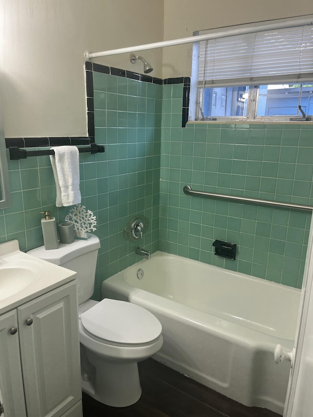 full bathroom with vanity, tiled shower / bath, toilet, tile walls, and wood-type flooring