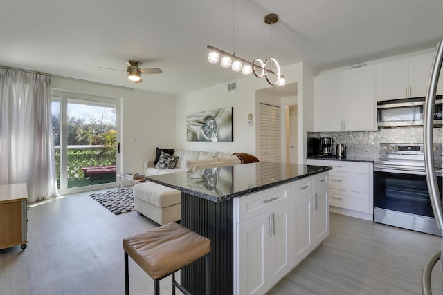 kitchen featuring pendant lighting, white cabinets, backsplash, dark stone counters, and stainless steel appliances