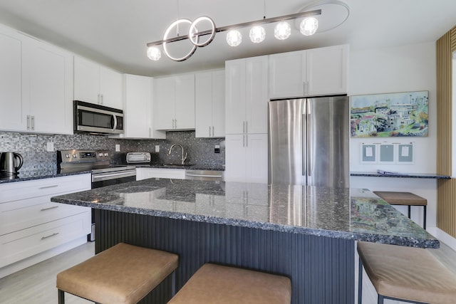 kitchen with pendant lighting, stainless steel appliances, and white cabinets