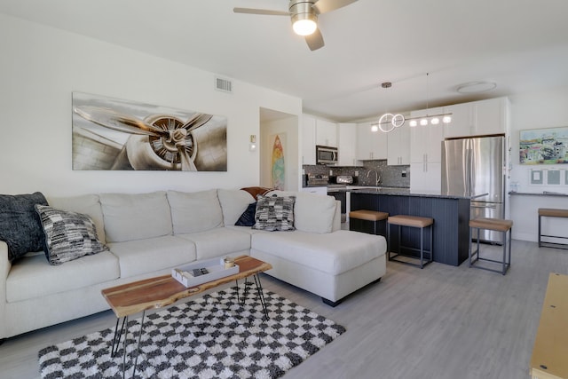 living room featuring ceiling fan and light hardwood / wood-style floors