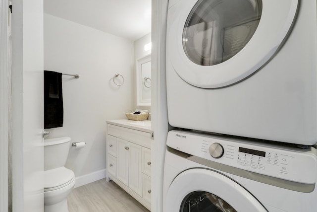 laundry room featuring light hardwood / wood-style flooring and stacked washer and clothes dryer