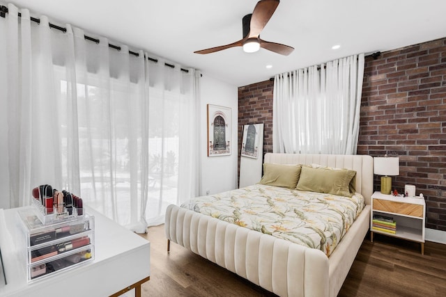 bedroom featuring brick wall, ceiling fan, and dark wood-type flooring