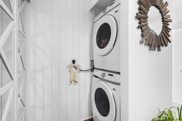 clothes washing area with stacked washer and dryer and wood walls