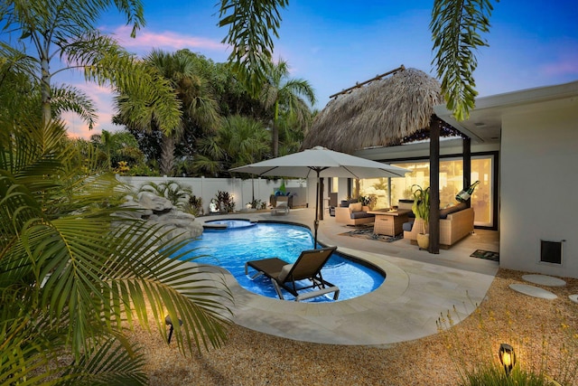 pool at dusk with a patio, an in ground hot tub, and outdoor lounge area