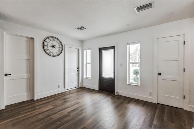 foyer entrance with a textured ceiling and dark hardwood / wood-style flooring