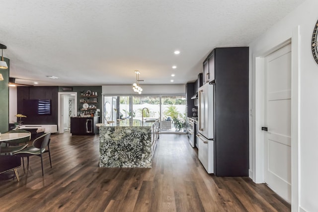 kitchen with high end white fridge, a center island, pendant lighting, dark hardwood / wood-style flooring, and a textured ceiling