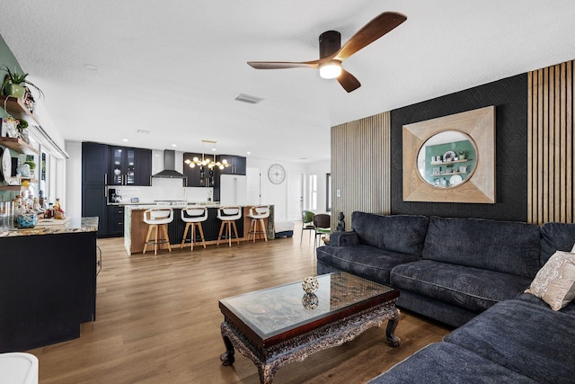 living room featuring a textured ceiling, dark wood-type flooring, a wealth of natural light, and ceiling fan with notable chandelier