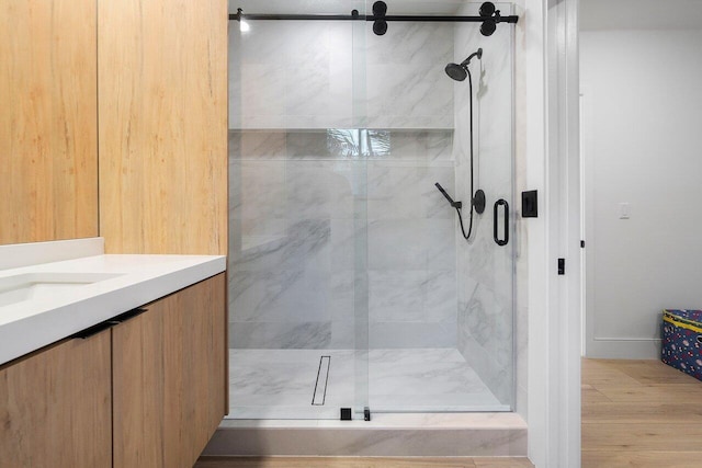 bathroom with hardwood / wood-style floors, vanity, and an enclosed shower