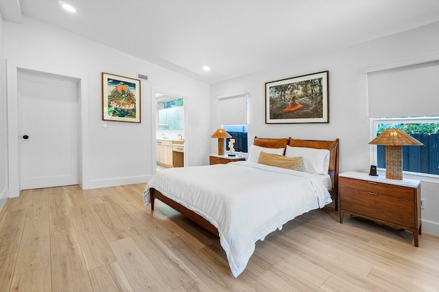 bedroom featuring connected bathroom and light hardwood / wood-style flooring