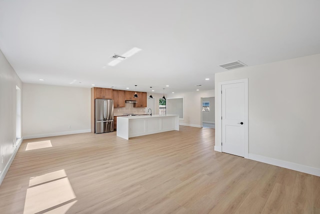 unfurnished living room with sink and light hardwood / wood-style floors