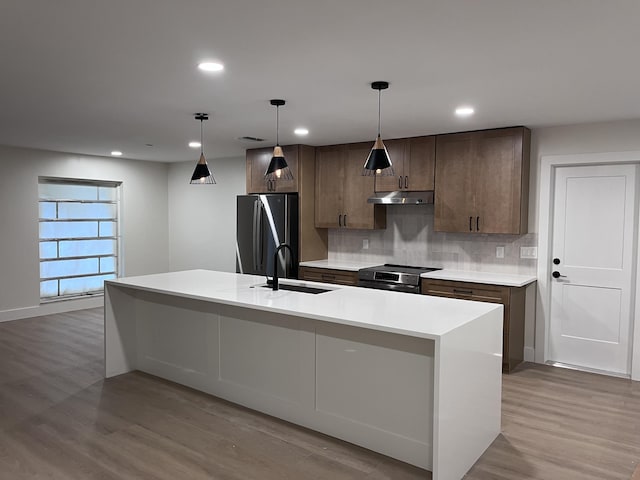 kitchen with sink, refrigerator, a kitchen island with sink, and stainless steel electric range oven