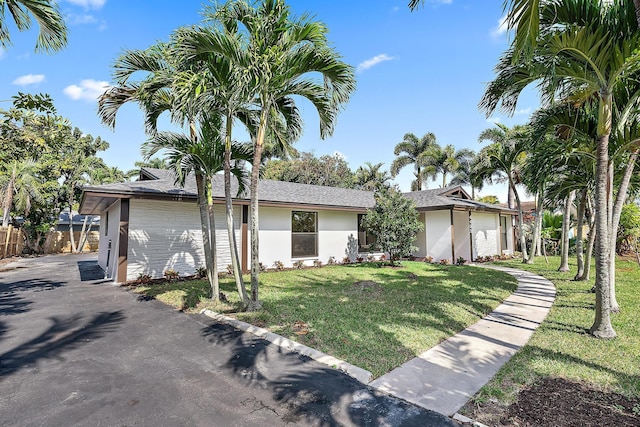 ranch-style home with a garage and a front lawn