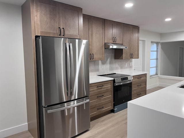 kitchen featuring light hardwood / wood-style floors, dark brown cabinetry, appliances with stainless steel finishes, and decorative backsplash