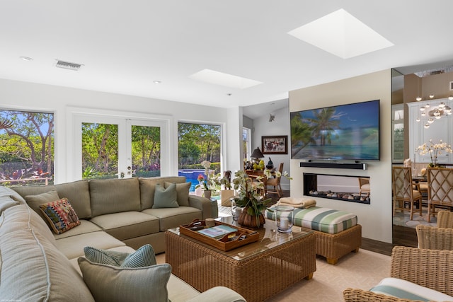 living room featuring lofted ceiling with skylight and french doors