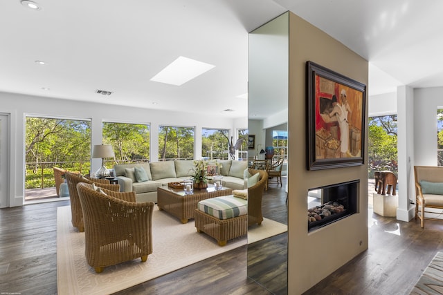 living room featuring a skylight, dark hardwood / wood-style floors, and a healthy amount of sunlight