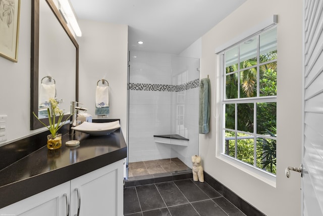 bathroom with a tile shower, tile patterned flooring, and vanity