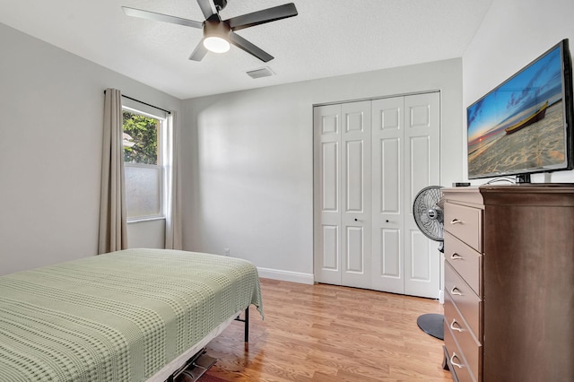 bedroom featuring a textured ceiling, a closet, ceiling fan, and light hardwood / wood-style floors