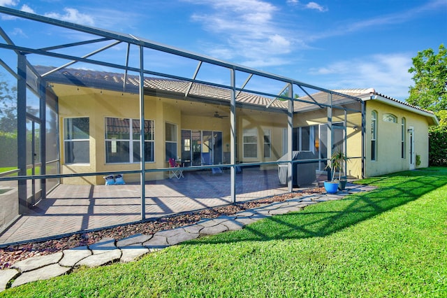 rear view of property featuring ceiling fan, a patio area, a lanai, and a yard