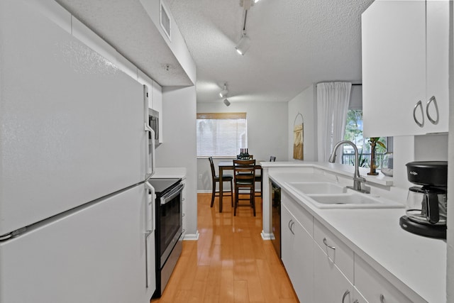 kitchen featuring sink, electric range, track lighting, white cabinets, and white fridge