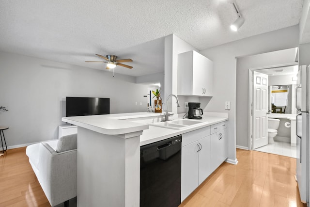 kitchen with a sink, black dishwasher, light wood-style flooring, and white cabinetry