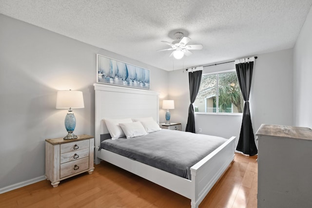 bedroom featuring a textured ceiling, ceiling fan, and light wood finished floors