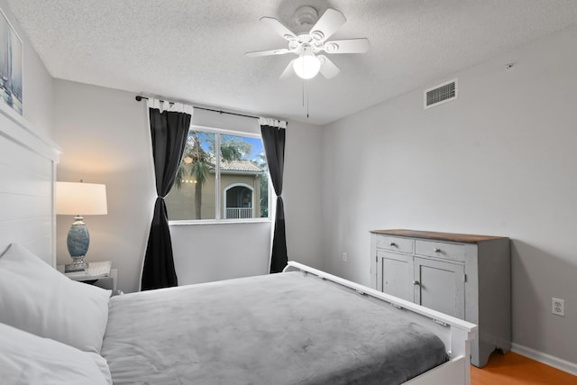 bedroom featuring a textured ceiling, ceiling fan, and light wood-type flooring