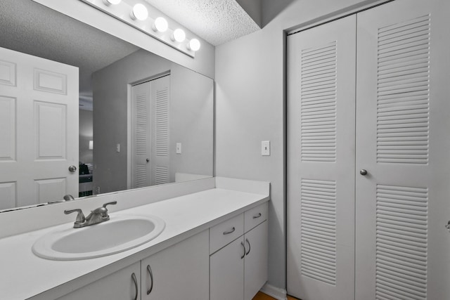 bathroom featuring a closet, a textured ceiling, and vanity