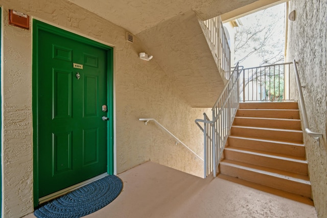 view of exterior entry featuring stucco siding and visible vents