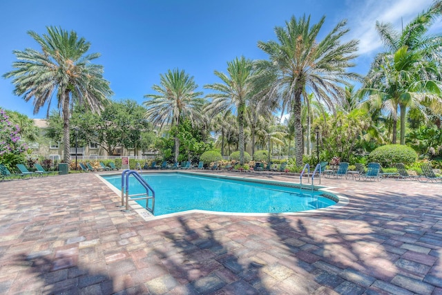 community pool with a patio area and fence